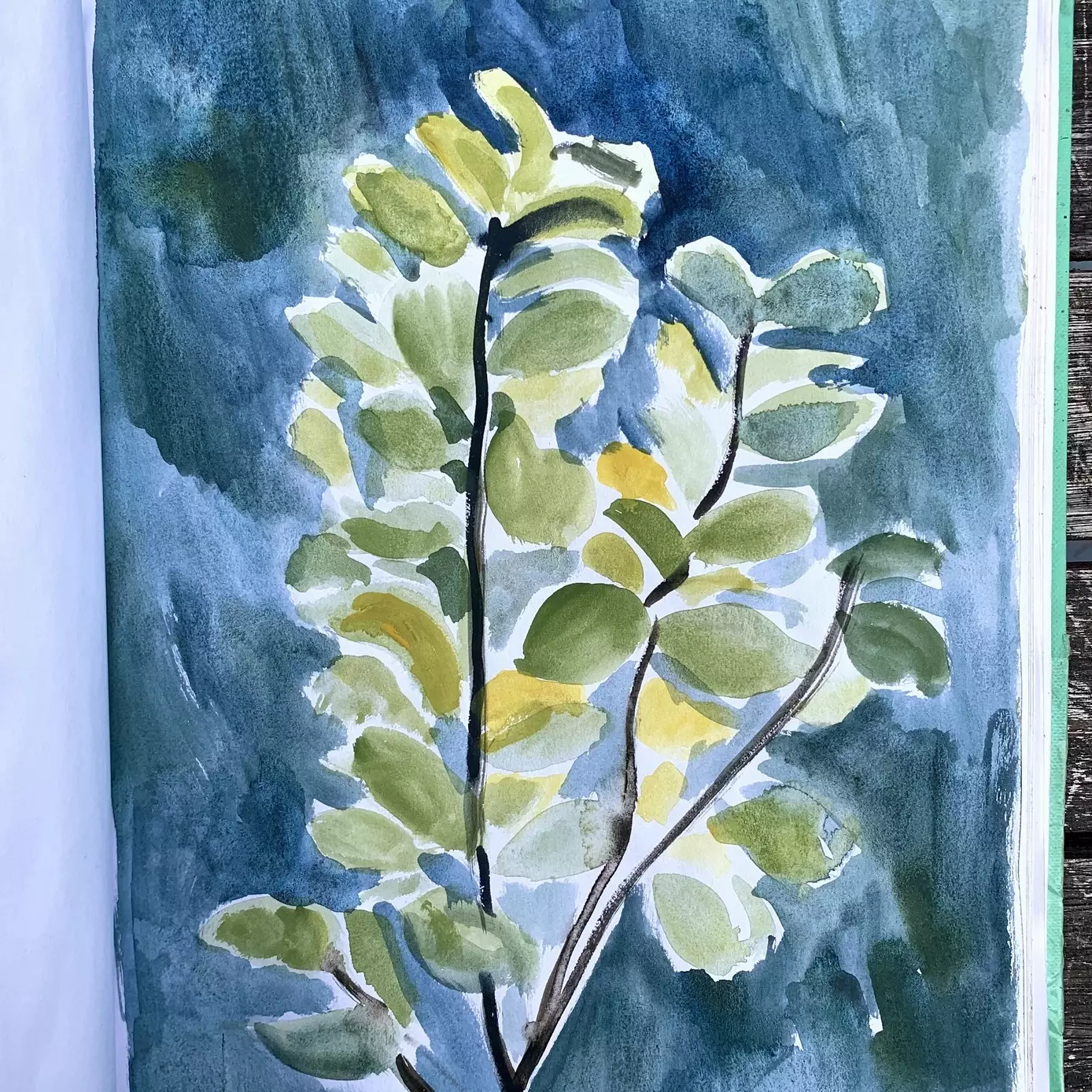 a sketchbook page of a painting of a tree. The close up painting shows the wide green curved leaves against a dark blue background 